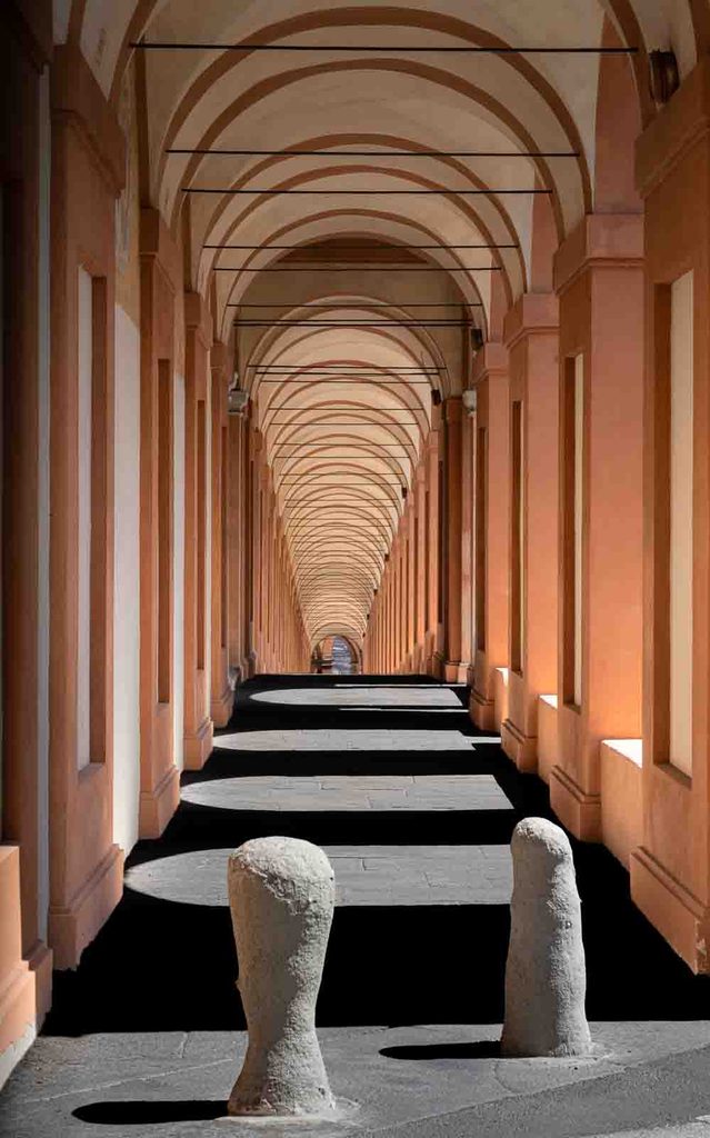 Sunlit arcade of the Portico di San Luca with alternating bands of light and shadow.