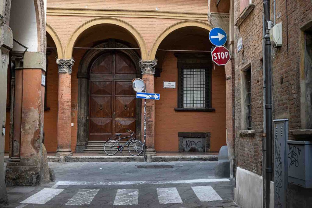 Street corner on Via Castiglione with arcades, bicycle, and historic buildings.