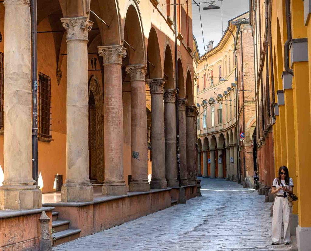 Arcaded section of Via Castiglione with stone columns and historic buildings.